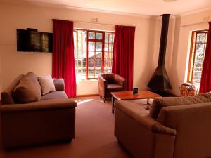 a living room with two couches and red curtains at Crane Cottage in Dullstroom