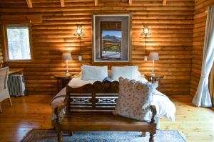 a bedroom with a bed and a mirror and a bench at Clarens Log Cabin in Clarens