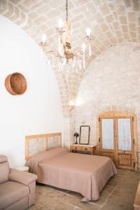 1 dormitorio con cama, sofá y lámpara de araña en Piazza Duomo - Medieval Puglia's House, en Giovinazzo