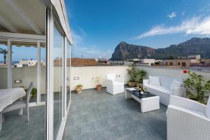 uma varanda com mobiliário branco e vista para as montanhas em Hotel Biancolilla em San Vito lo Capo