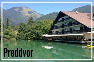 a hotel on a lake with mountains in the background at Tomas Old House - River Apartments in Visoko