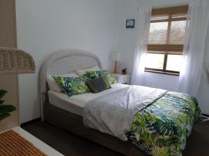 a bedroom with a bed with pillows and a window at Abbey Beach Cottage in Busselton