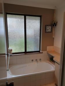 a bath tub in a bathroom with a window at Abbey Beach Cottage in Busselton