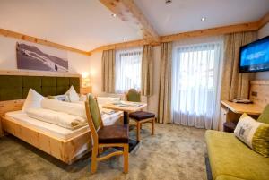 ein Hotelzimmer mit einem Sofa, einem Tisch und einem TV in der Unterkunft Garni Birkenheim in Gerlos + 49 Fotos