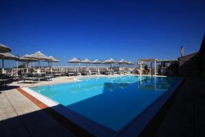 a large blue swimming pool with chairs and umbrellas at ThE LAB in Casale Marittimo