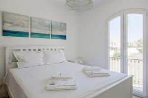 a white bedroom with a bed with two towels on it at FLH Altura Family House with Pool in Altura +31 photos