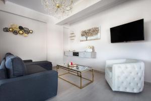 Royalty Suites Loft في نيكيتي: غرفة معيشة مع أريكة وطاولة وتلفزيون