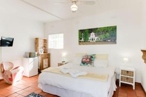 1 dormitorio con 1 cama blanca y TV en Albourne Guesthouse, en Somerset West