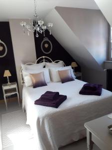 1 dormitorio con 1 cama blanca grande con almohadas moradas en Chambre d'hote Chez Liz en Maslives