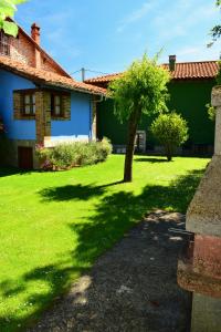 a green yard with a tree and a house at La Cabada in Ortiguero