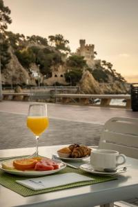un vaso de zumo de naranja sentado en una mesa con comida en Hotel Rosamar Maxim 4*- Adults Only, en Lloret de Mar