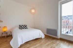 - une chambre blanche avec un lit et une fenêtre dans l'établissement Le Minot, à Marseille