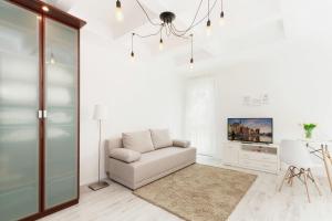 a white living room with a couch and a tv at Apartments Gdańsk Dworska by Renters in Gdańsk