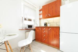 kuchnia z drewnianymi szafkami i białą lodówką w obiekcie Apartments Gdańsk Dworska by Noclegi Renters w Gdańsku
