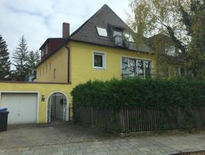 a yellow house with a fence in front of it at Villawöl in Munich