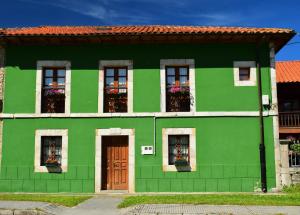 a green house with windows and a door at La Cabada in Ortiguero