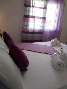 a bedroom with a bed with towels and a window at Nikoletta Rooms in Parikia