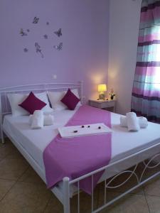 una camera da letto con un grande letto bianco con lenzuola e cuscini viola di Nikoletta Rooms a Paroikia