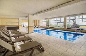 a pool with chaise lounge chairs and a swimming pool at H10 Salauris Palace in Salou