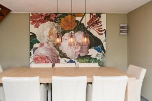 a dining room table with white chairs and a painting at Vakantiehuizen 7Huizen aan Zee in Scharendijke
