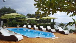 a pool with chairs and umbrellas on a deck at Banjol 441 Apartman mare in Rab