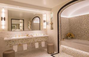 a bathroom with a sink, mirror, and bathtub at Four Seasons Hotel London at Ten Trinity Square in London