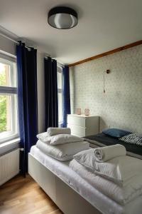 a room with four beds with blue curtains at Apartamenty toruńskie pod Krzywą Wieżą in Toruń