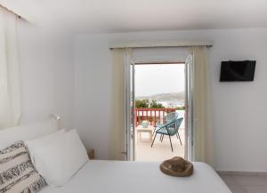 a white bedroom with a bed and a balcony at Hotel Charissi in Mikonos