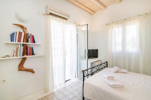 Un dormitorio blanco con una cama y una ventana. en Vincenzo Family Rooms, en Tinos 96 fotos más