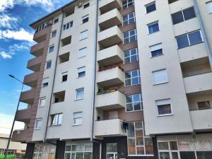 een groot wit appartementencomplex met ramen bij Apartman Centar in Doboj