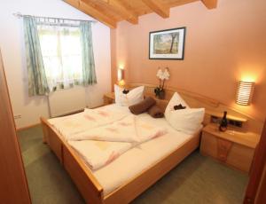 1 dormitorio con 1 cama grande con sábanas y almohadas blancas en Ferienwohnungen Anita, en Fieberbrunn