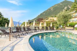 a pool at a resort with chairs and umbrellas at Hotel Cristina in Limone sul Garda
