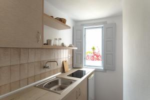 kuchnia ze zlewem i oknem w obiekcie Evgenia Rooms and Apartments w mieście Chora Folegandros