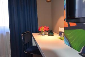 a desk with a vase of flowers on it at Blue Mansion Hotel in Aalsmeer