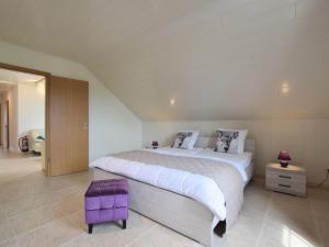 um grande quarto branco com uma cama grande e banco roxo em Quaint Apartment in Vielsalm with Private Terrace em Vielsalm