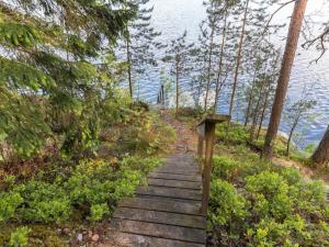 un chemin en bois menant à une colline avec l'eau dans l'établissement Holiday Home Artturin mökki by Interhome, à Kylmälä