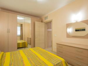 マリーナ・ディ・ビッボーナにあるApartment Relais-1 by Interhomeのベッドルーム(黄色のベッド1台、鏡付)