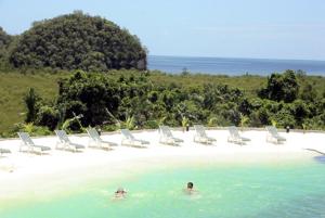 a group of chairs and people in the water on a beach at Airai Water Paradise Hotel & Spa in Koror