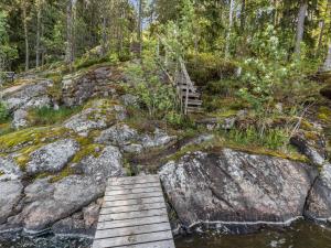 uma ponte de madeira sobre um rio numa floresta em Holiday Home Artturin mökki by Interhome em Kylmälä