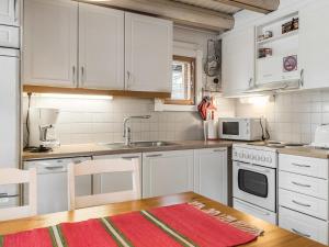 アカスロンポロにあるHoliday Home Riekonmarja by Interhomeの白いキャビネットと木製テーブル付きのキッチン