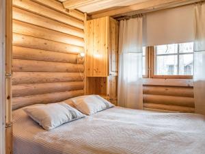 a bedroom with a bed with wooden walls and a window at Holiday Home Riekonmarja by Interhome in Äkäslompolo