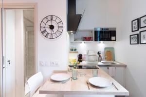 a kitchen with a table and a clock on the wall at Le Petit Botte in Rennes