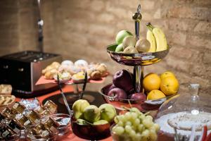 a table topped with bowls of fruits and vegetables at Palazzetto Rosso - Art Hotel in Siena