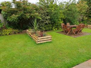 ogród z drewnianym stołem, krzesłami i trawą w obiekcie Holiday Home Woodhouse-4 by Interhome w mieście Shermanbury