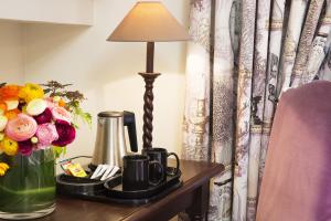 a table with a lamp and a vase of flowers at Castex Hotel in Paris