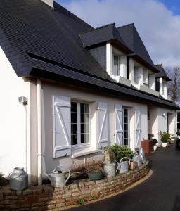 une maison blanche avec des plantes en pot sur un mur de briques dans l'établissement Chambre dans villa, à Gouesnou