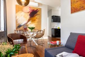 sala de estar con mesa, sillas y una pintura en Imperial Luxury & Modern Apartment en Sevilla
