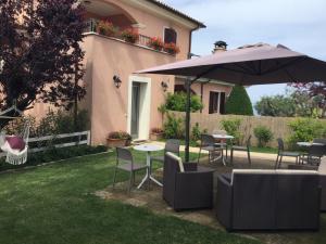 patio ze stołami, krzesłami i parasolem w obiekcie Ellebì B&B w mieście Montone
