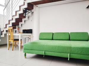 a green couch in a living room with a staircase at AirTLV - Centrally Located Studio With Gallery in Tel Aviv