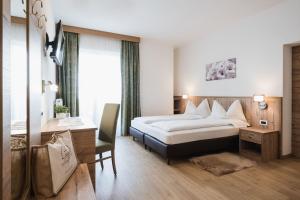 a hotel room with a bed and a desk at Laguscei Dolomites Mountain Hotel in Arabba